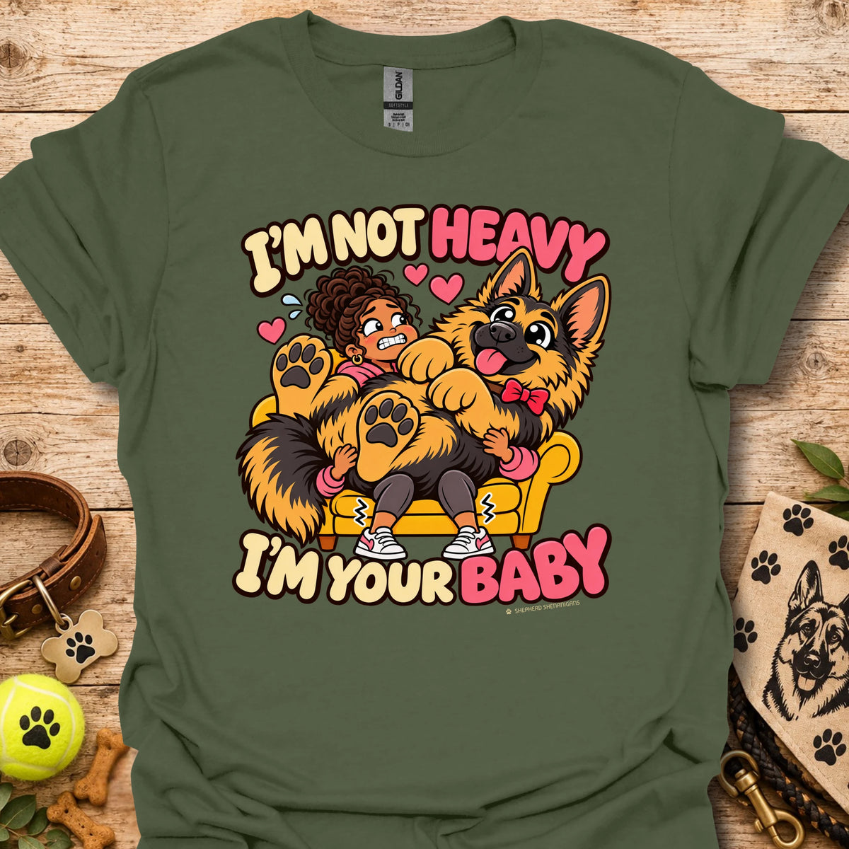Military green T-shirt with a colorful child and dog graphic and “I'm Not Heavy I'm Your Baby” text