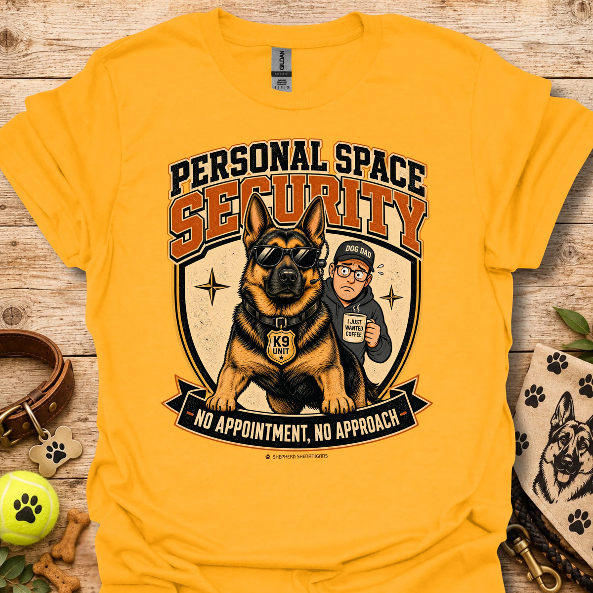 Gold T-shirt with a security dog and handler graphic and bold lettering.