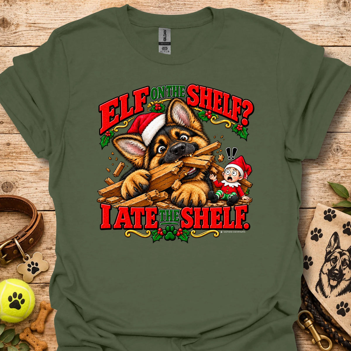 Olive green graphic t-shirt with cat-and-wood “Elf on the Shelf?” and “I ate the shelf” print
