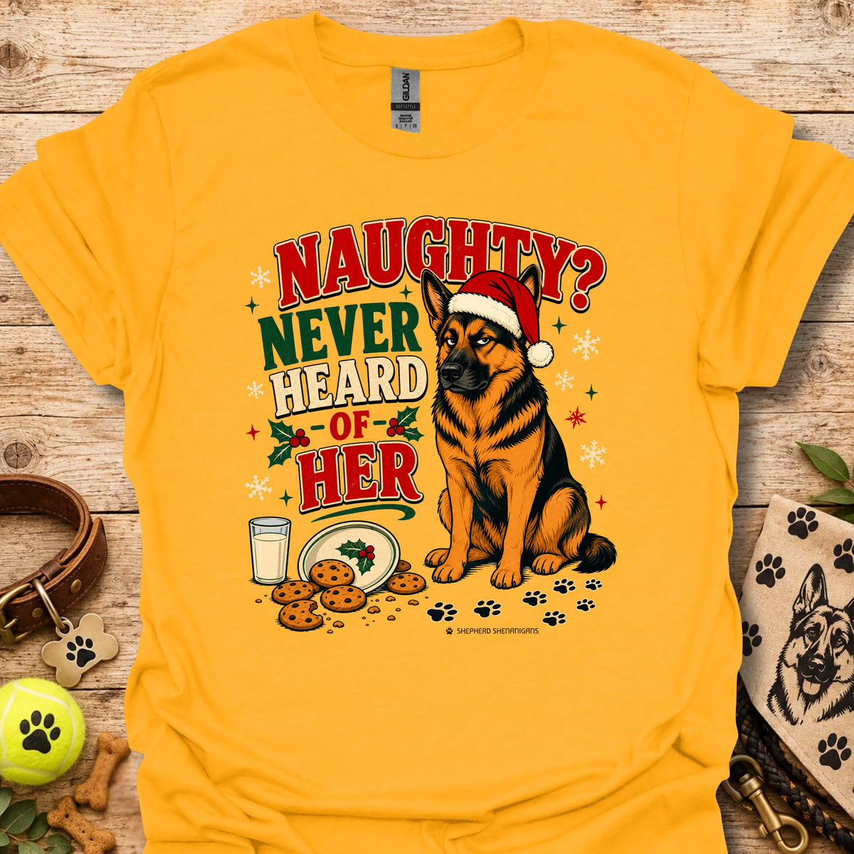 Gold graphic t-shirt with dog in Santa hat, mug of milk, and 'Naughty? Never Heard of Her'