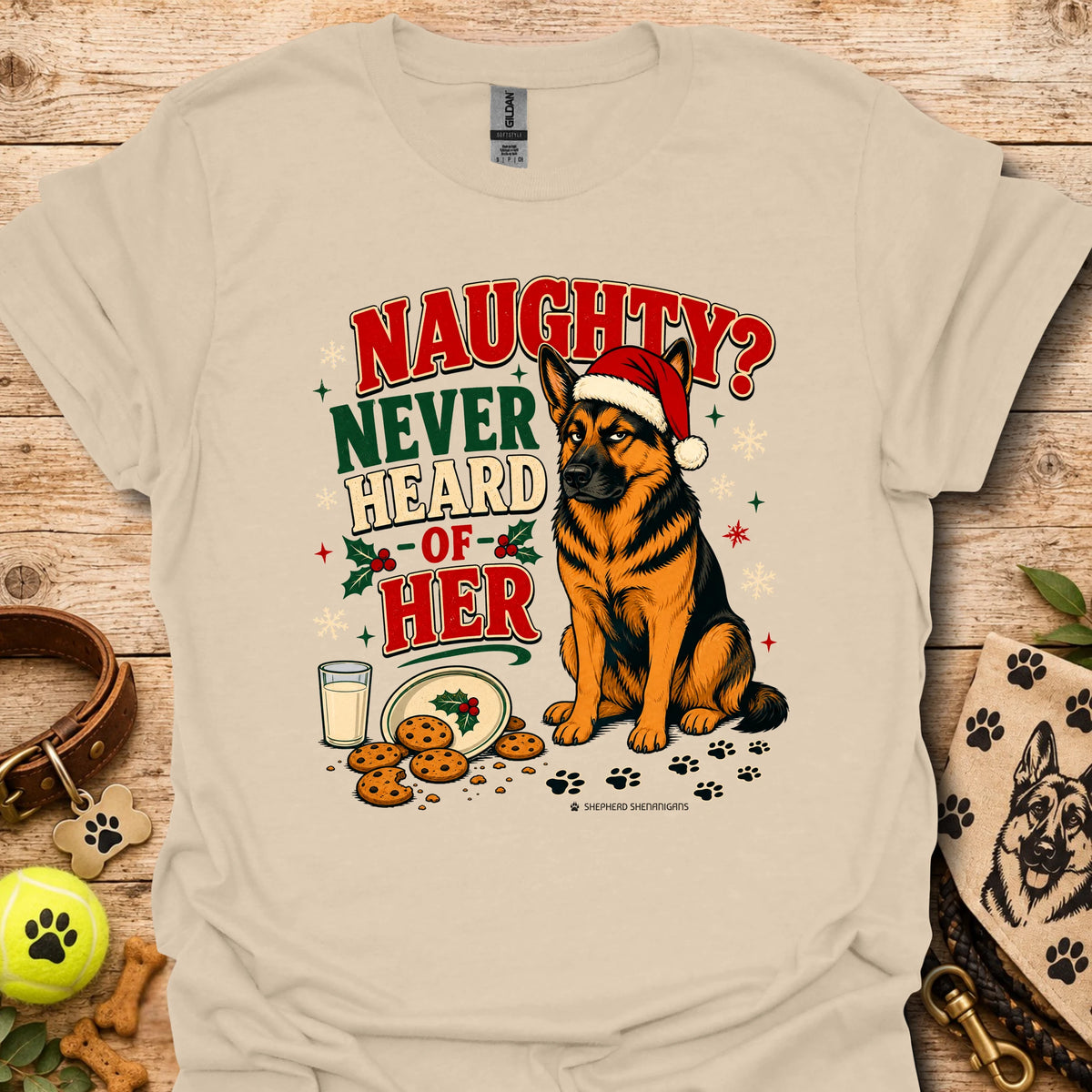 Sand graphic t-shirt with dog in Santa hat, cookies, and 'Naughty? Never Heard of Her'