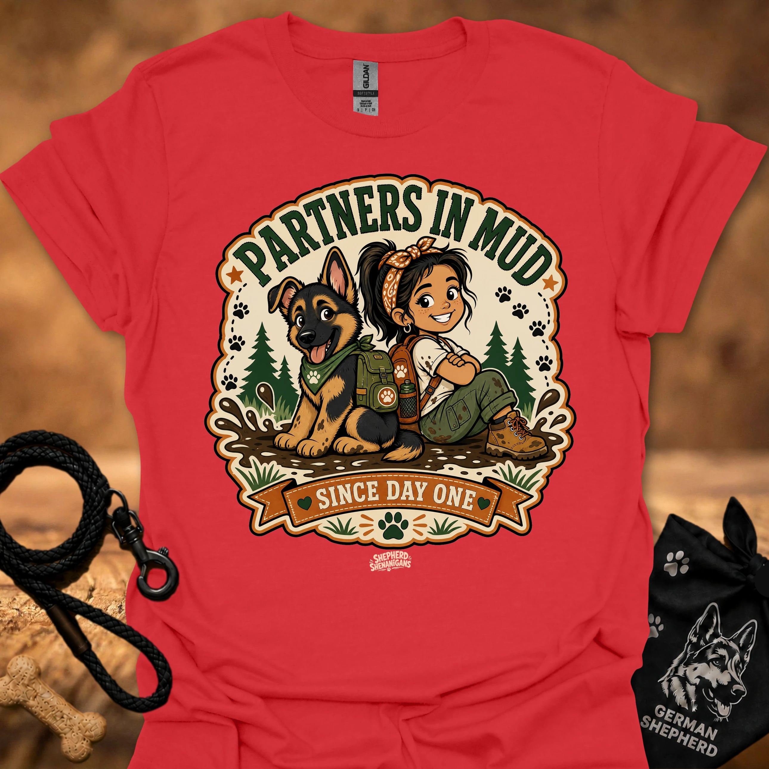 Red women’s t-shirt with “Partners in Mud” dog and girl graphic with banner