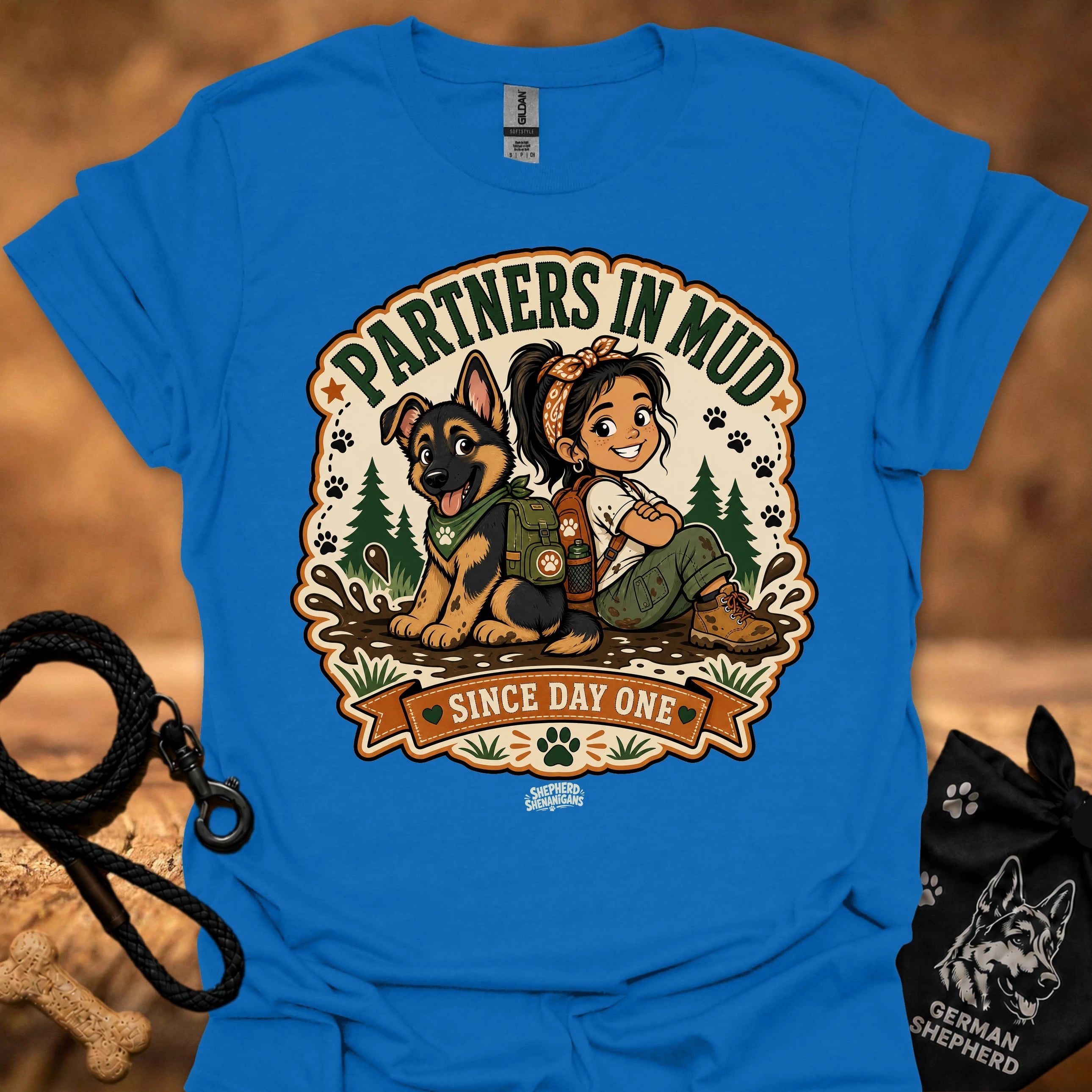 Royal blue women’s t-shirt with “Partners in Mud” dog and girl “Since Day One” graphic