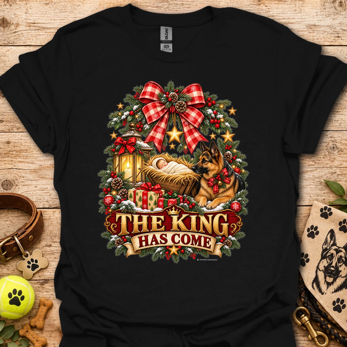 Black holiday graphic T-shirt with wreath, dog, and “THE KING HAS COME” print