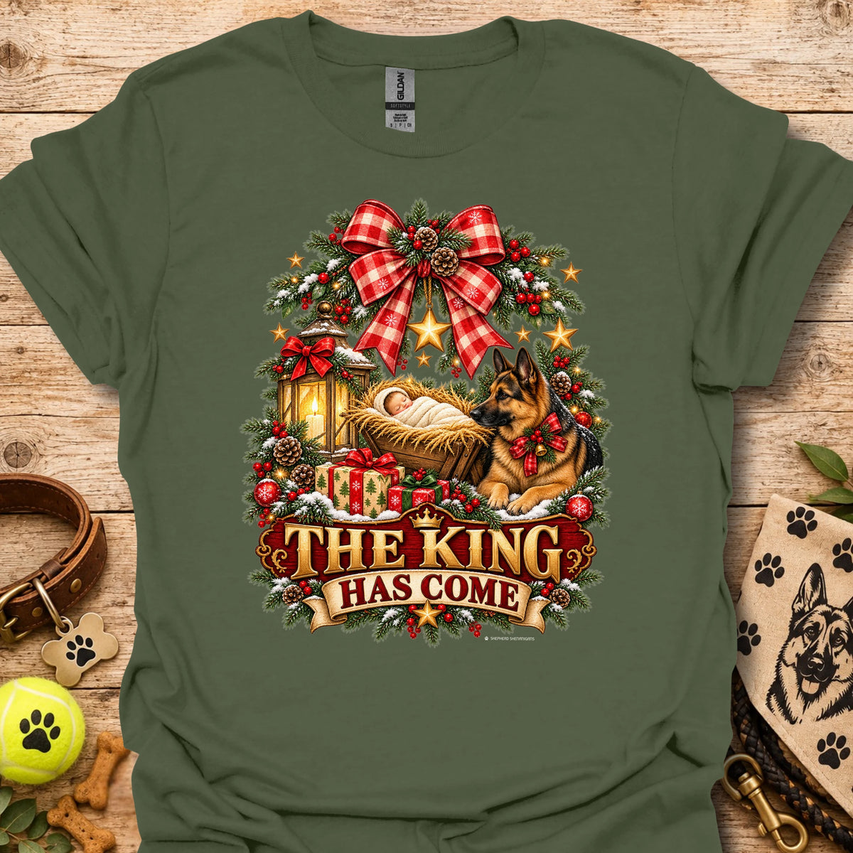 Military green holiday graphic T-shirt with wreath, dog, and “THE KING HAS COME” print
