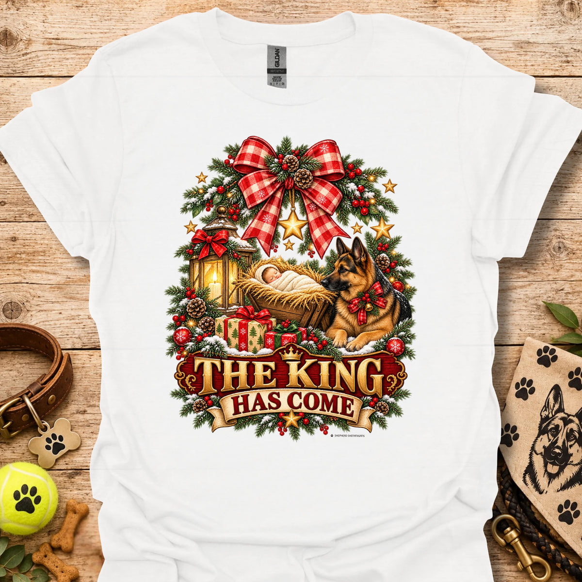 White holiday graphic T-shirt with wreath, dog, and “THE KING HAS COME” print